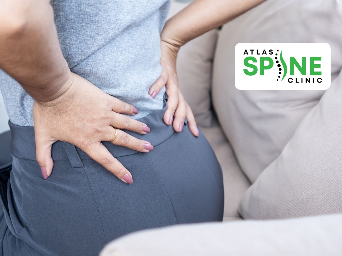 Person sitting on a sofa holding one side of the low back and buttock in pain