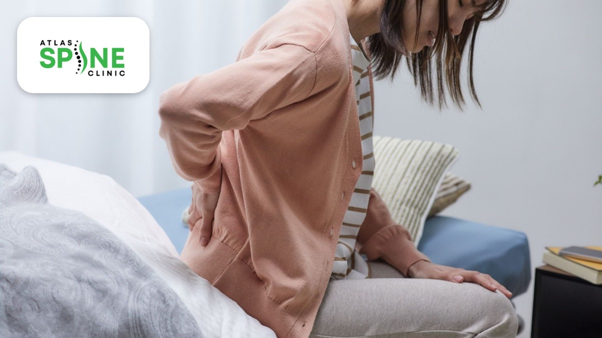 Woman with sacroiliac and low back pain holding her lower back while sitting