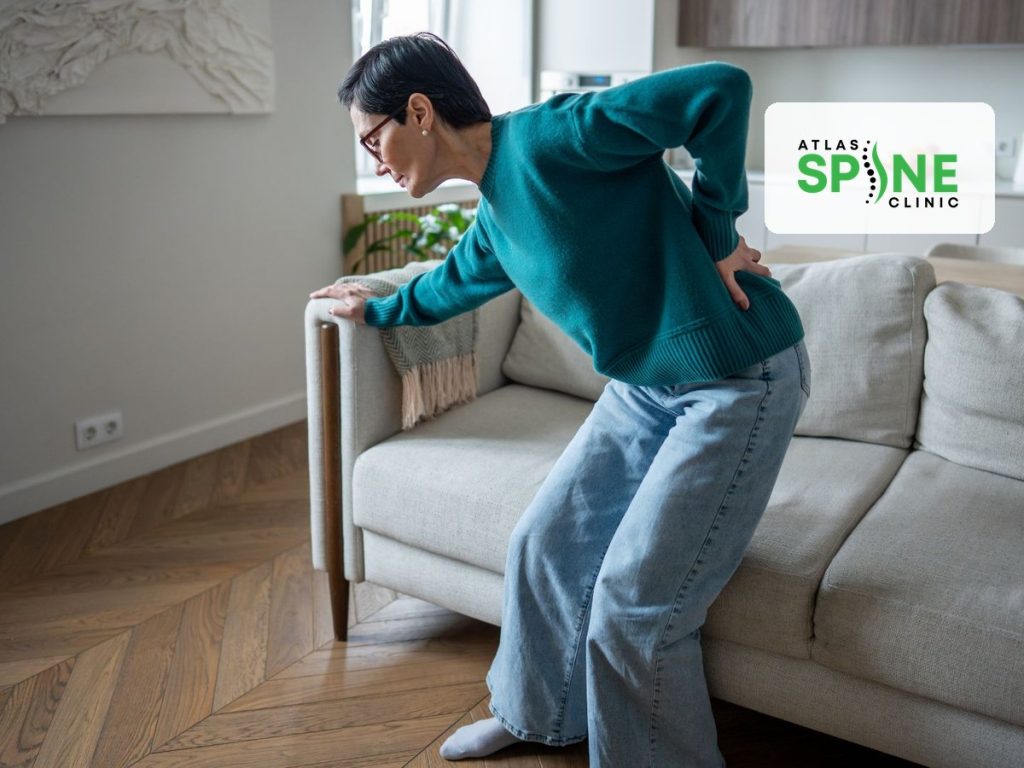 Woman with lower back pain rising from a couch, herniated disc care at Atlas Spine Clinic in Scarborough